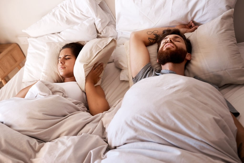 woman getting annoyed from husband suffering from sleep apnea and snoring
